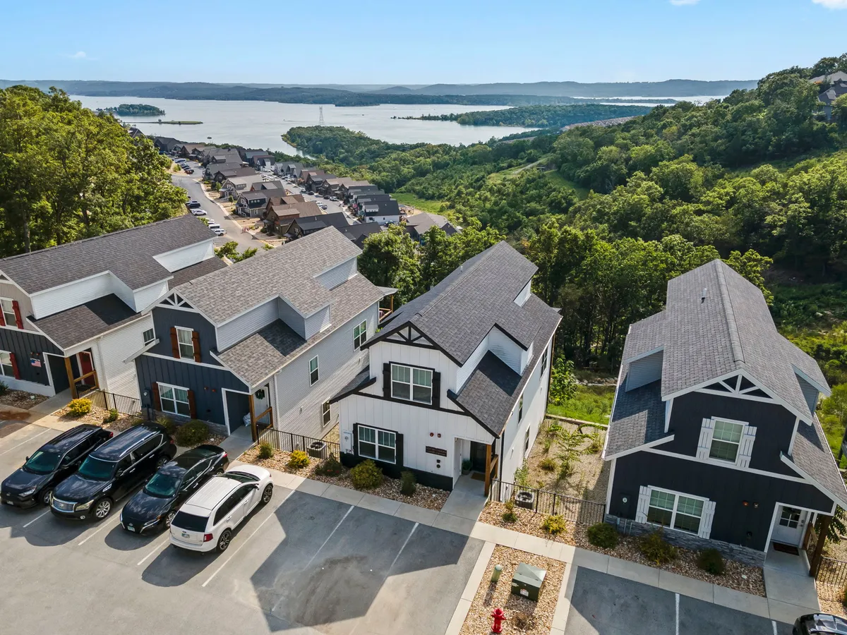 A tranquil exterior scene featuring modern residential buildings set against a beautiful lakeside backdrop. There is lush greenery surrounding the area, with walking paths that invite outdoor exploration. The image captures serene community spaces perfect for leisurely strolls with pets. The presence of the lake and natural surroundings emphasizes the property’s proximity to outdoor adventure and pet-friendly activities.