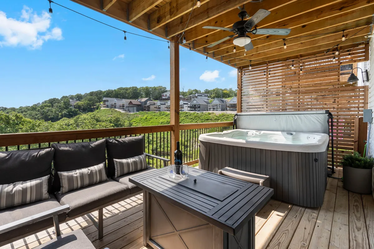 An inviting outdoor hot tub sits on a deck, bordered by comfortable seating and offering a view of the surrounding landscape. The setting is private, serene, and perfect for relaxation, with space for friends or family to gather outdoors.