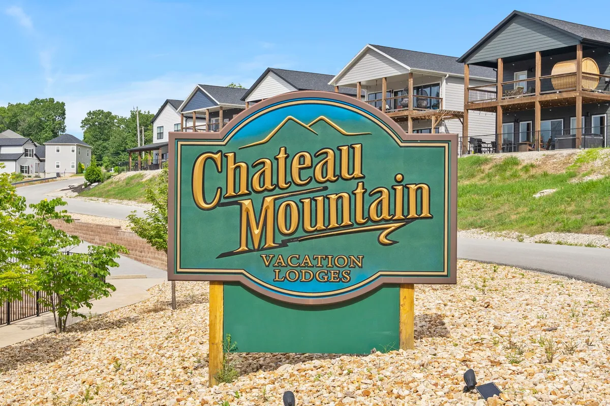 A welcoming exterior featuring the Chateau Mountain sign and inviting vacation lodges nestled in a landscaped setting. The image evokes a sense of arrival at a pet-friendly getaway, with open spaces and trails in the background hinting at the recreational opportunities nearby.